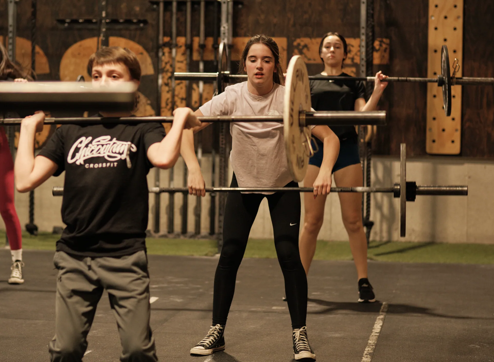 Trois jeunes athlètes Concentration sport en position front squat avec barre olympique.